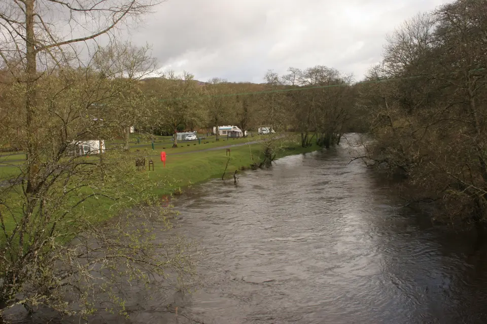 Caravans and tents on the grass beside the River Forth at Cobleland Campsite