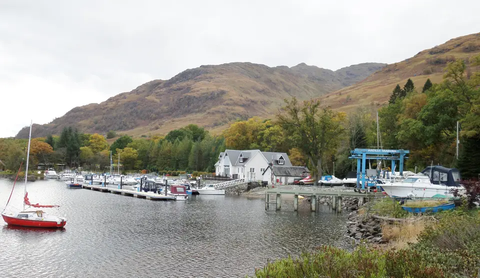 Ardlui marina with moored boats, floating pontoons and a boat lift below wooded hills