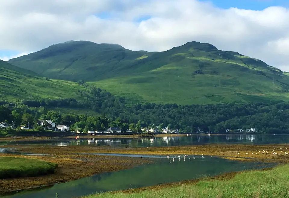 Arrochar on the shore of Loch Long, with a steep green hill rising behind the village