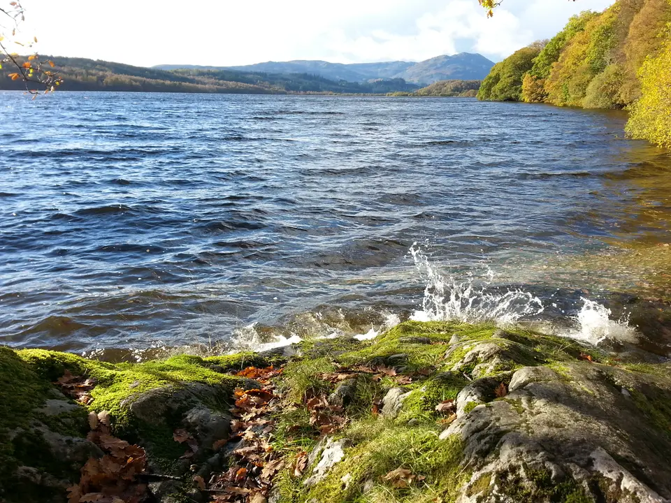 Waves breaking on a mossy shore of Loch Venachar in autumn light
