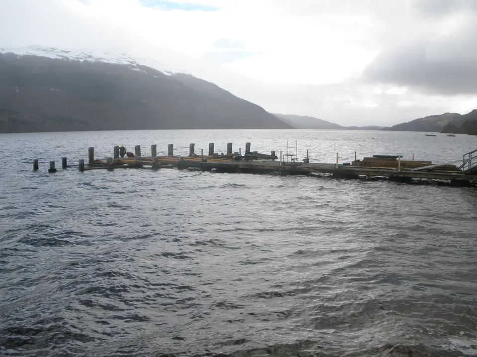 Tarbet Pier jutting into Loch Lomond with hills across the water