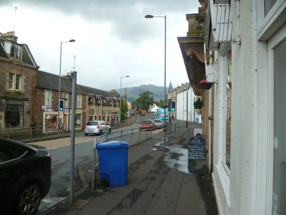 Looking down Callander’s main street past shop fronts, with a hill in the distance