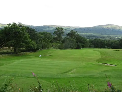 A green and bunker at Killin Golf Club with hills behind