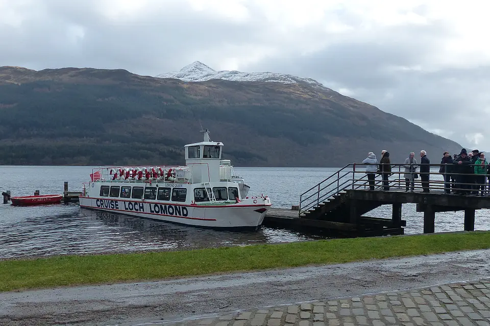 A Cruise Loch Lomond boat moored at Tarbet Pier with a snow-capped hill behind