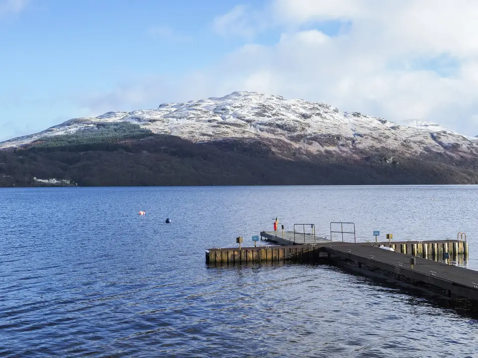 A floating jetty on Loch Lomond at Inveruglas with a snow-dusted hill across the water