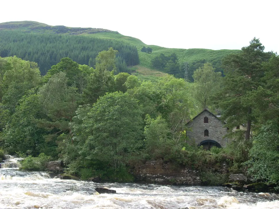 A small stone building among trees above the rapids at Killin