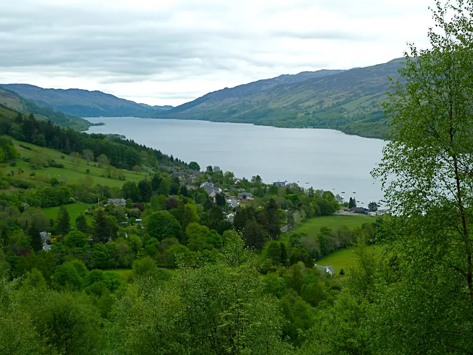 Loch Earn seen from above Lochearnhead, with green hills on both shores and a village below