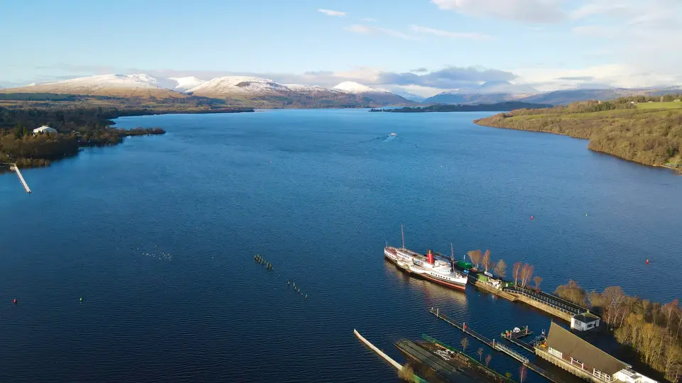 Loch Lomond seen from above Balloch, with the paddle steamer Maid of the Loch moored at the pier and hills across the water
