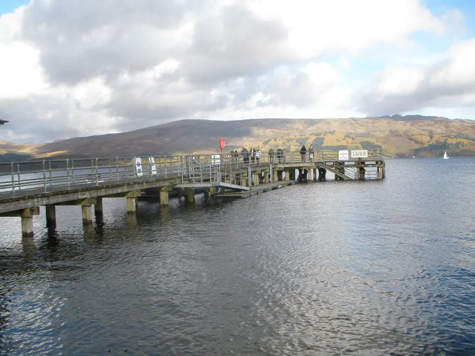 Luss pier seen from the shore, with hills behind