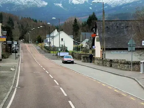 The main road running through Strathyre village with white houses and a shop beside it