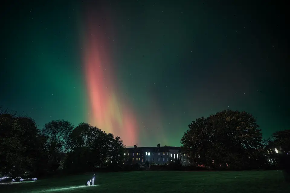 Green and purple northern lights glowing over the Edinburgh skyline at night