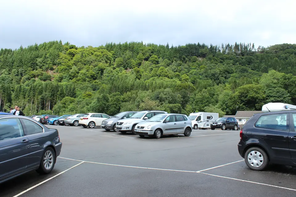 Cars parked in the Station Road car park at Callander with a wooded hill rising behind