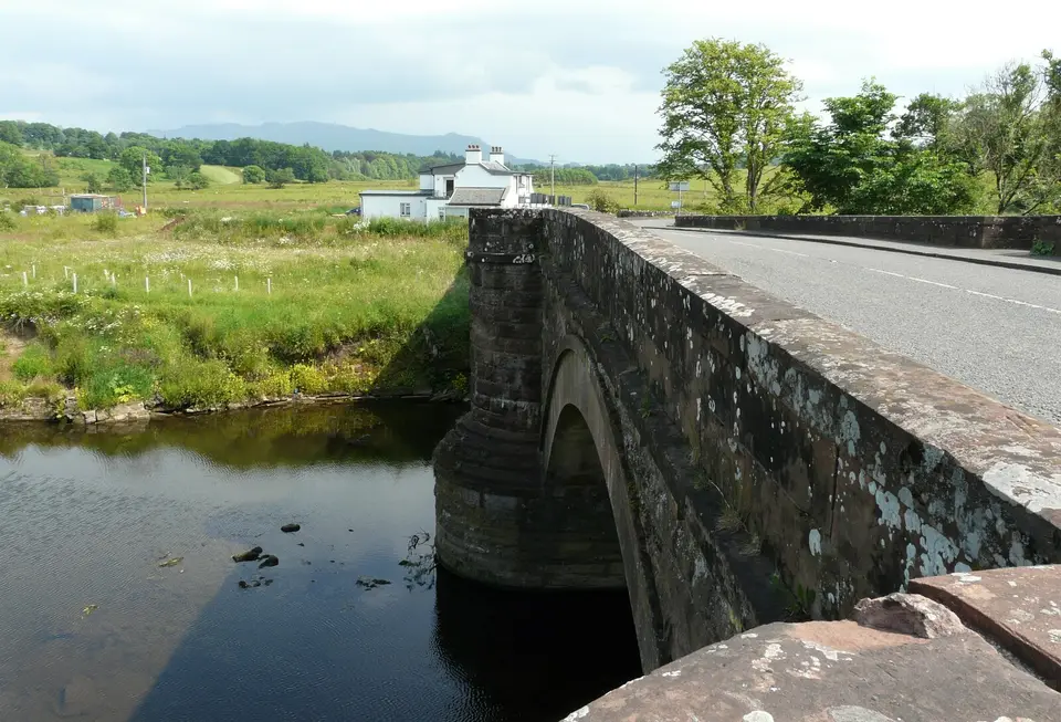 A stone road bridge over the water at Drymen, with fields beyond