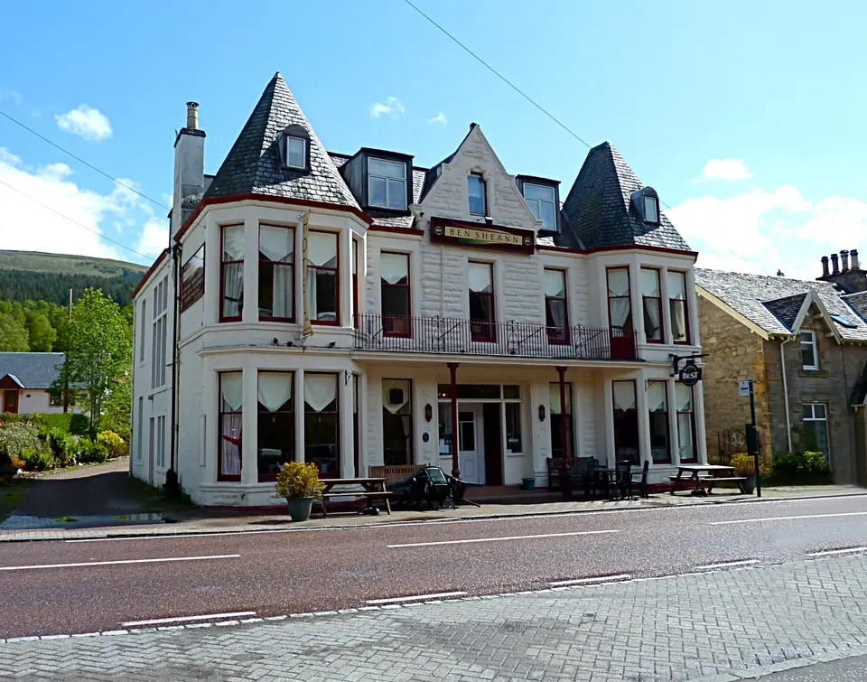 A large cream building with turrets and bay windows beside the main road through Strathyre
