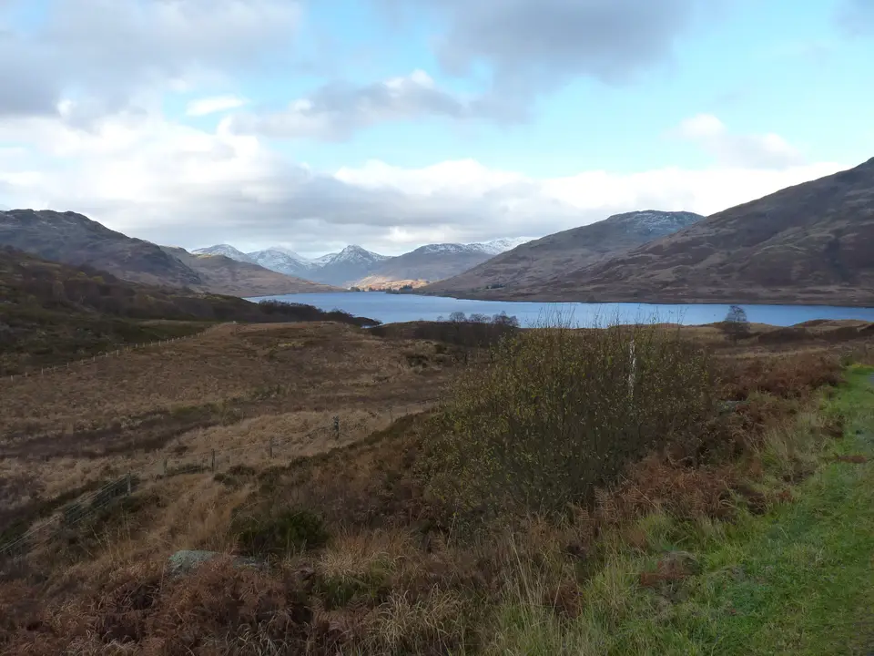 Heather hills in the Trossachs with a loch in the distance under a cloudy sky
