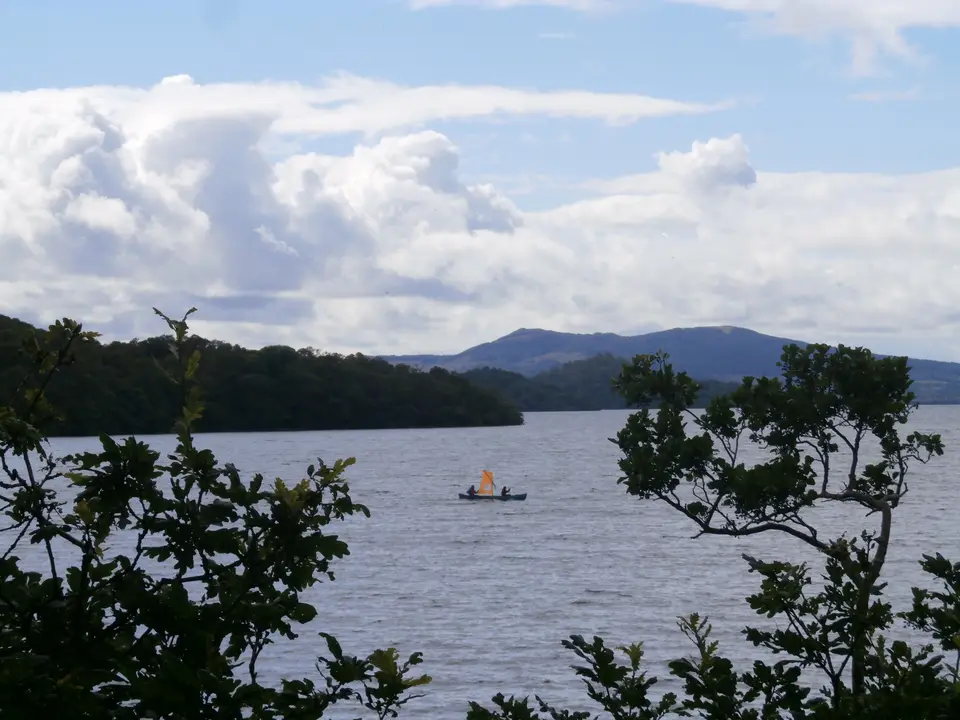 A sailing canoe under sail on Loch Lomond on a bright day